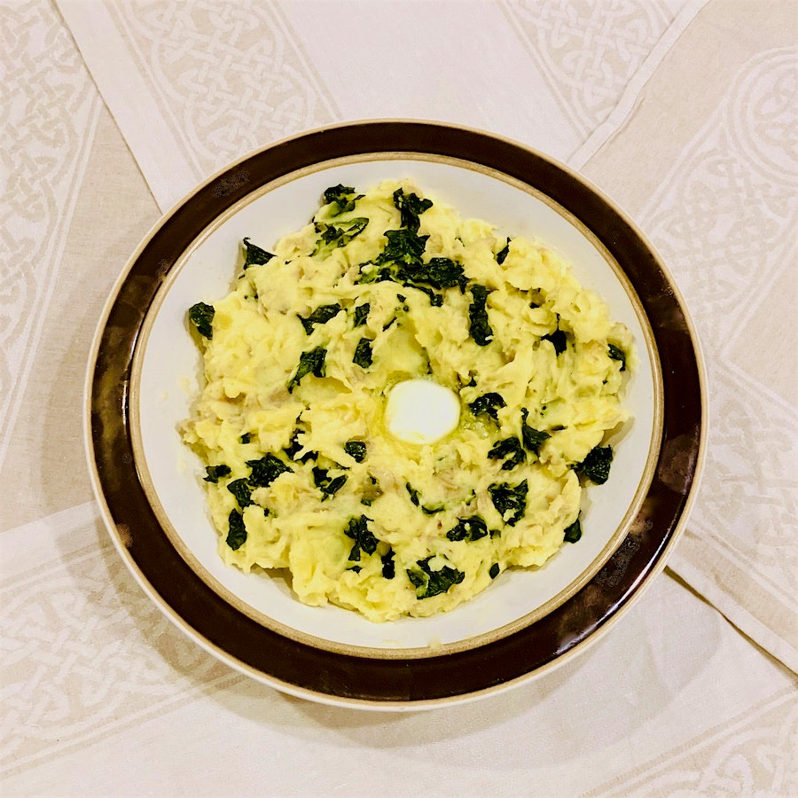 A bowl of colcannon mashed potatoes with a pat of melted butter in the center